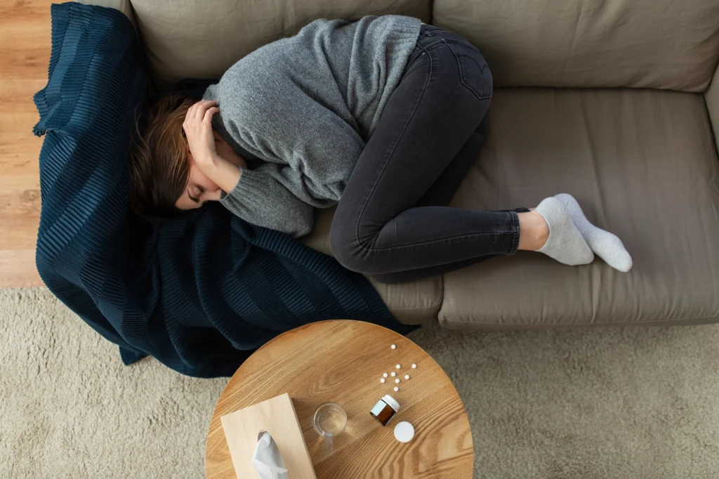 Suboxone Withdrawal: A woman on a couch on her side with her knees pulled up and her arms wrapped around herself.