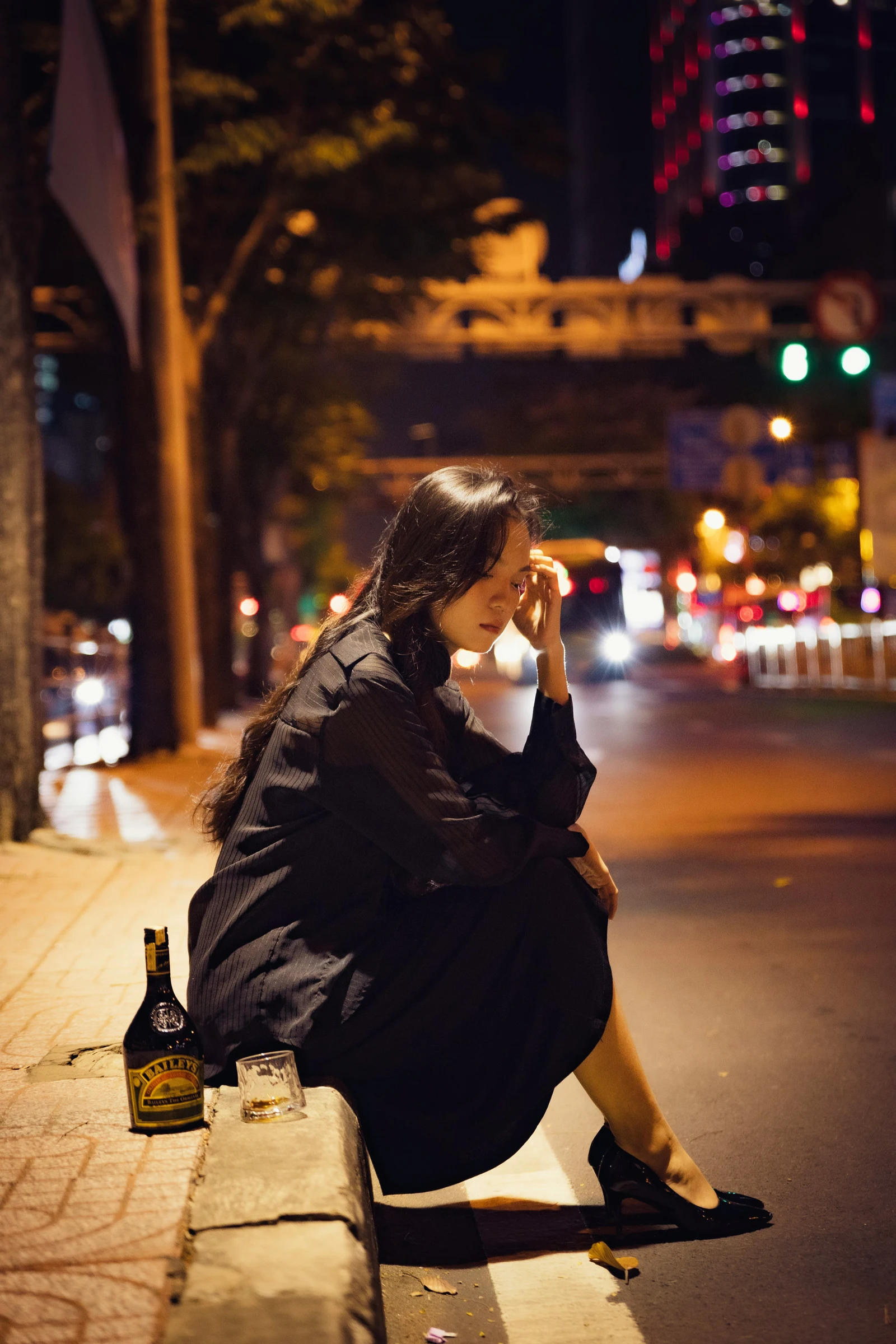 Woman with drunk eyes on the sidewalk with a bottle of beer next to her