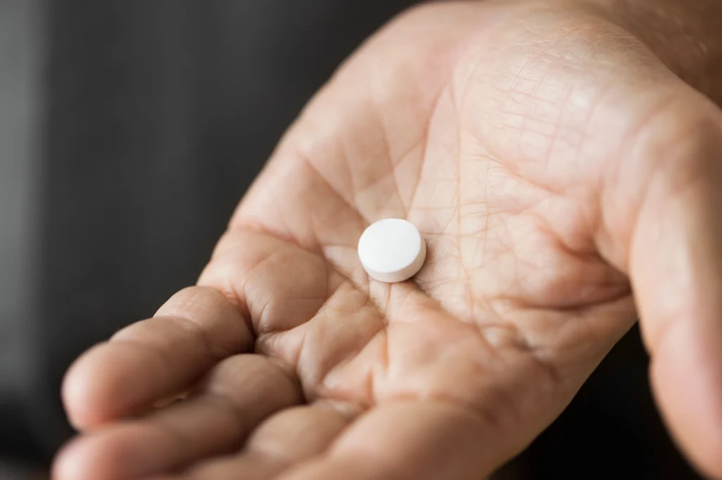 an open hand holding a single white pill; can you mix cialis and alcohol?