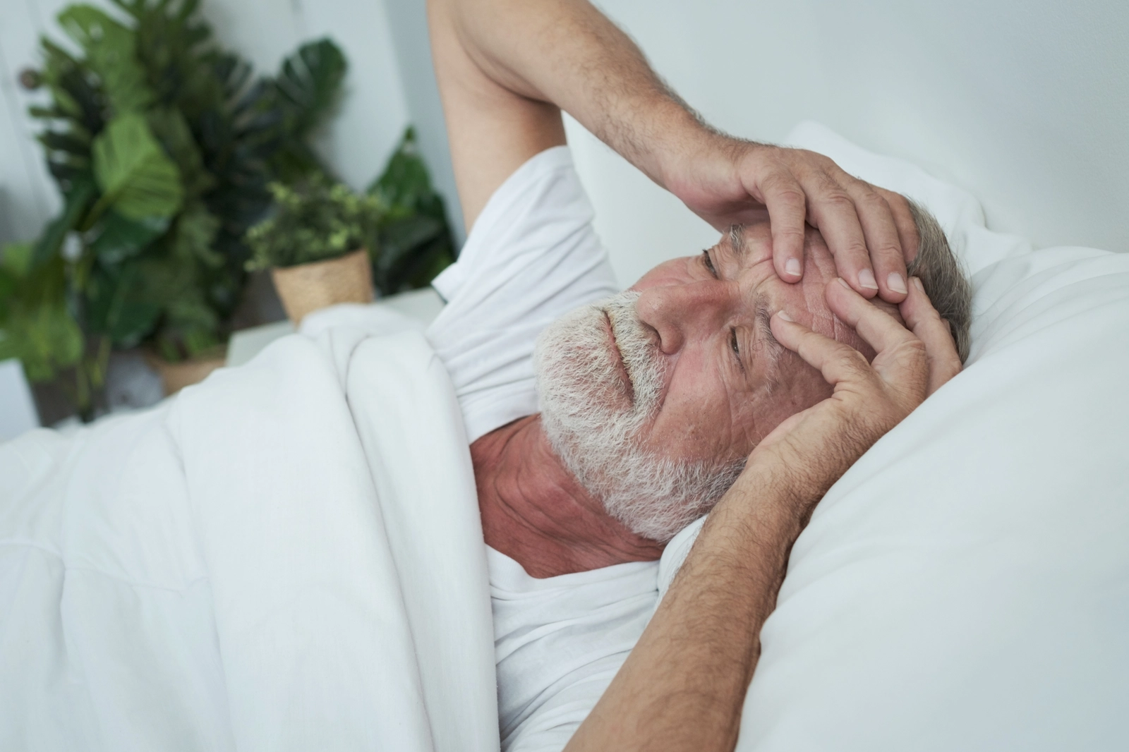 man in bed with aching head