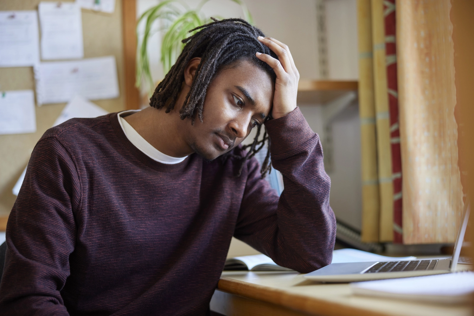 BIPOC Mental Health Month: An individual sitting at a desk with a hand to his head.