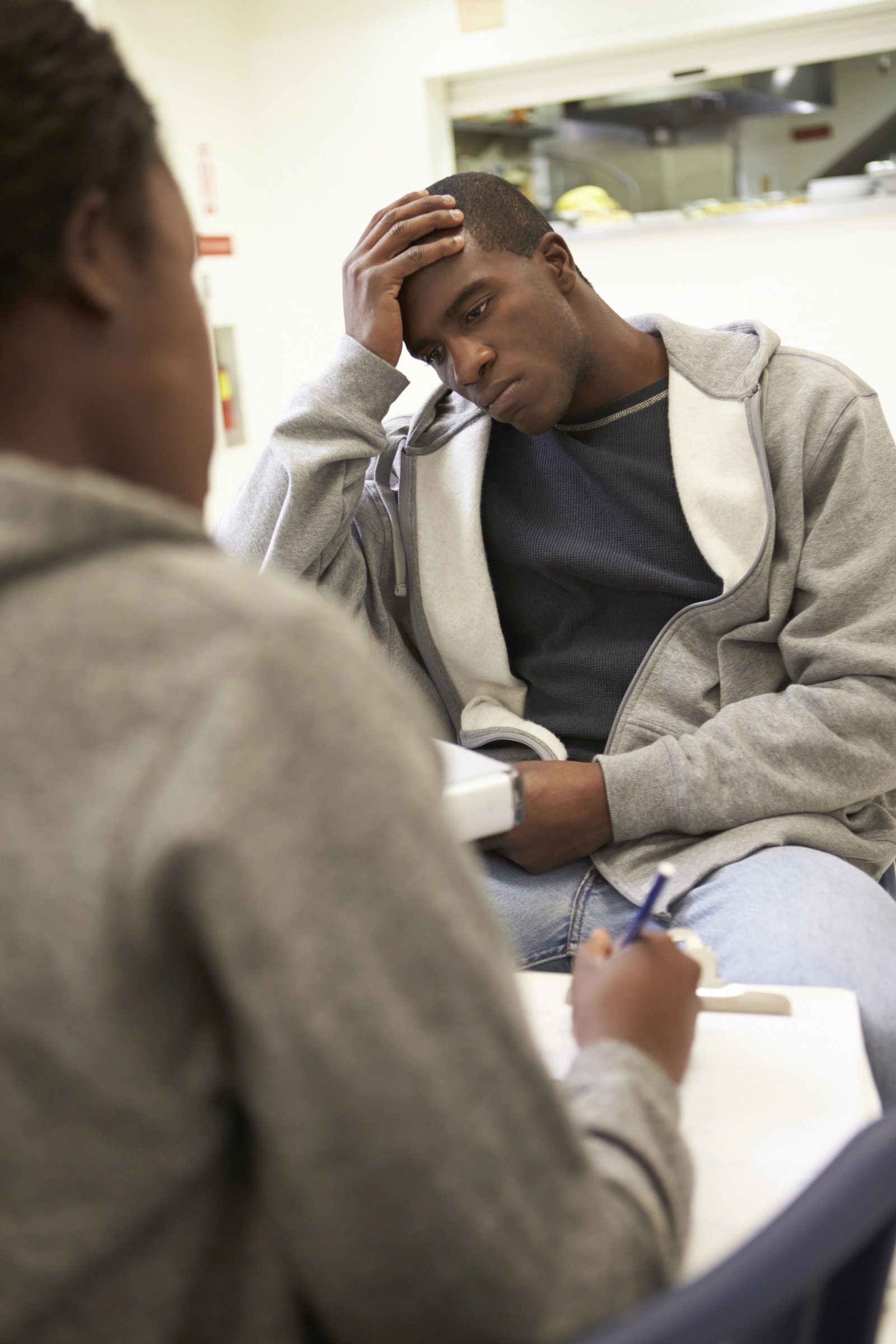 BIPOC Therapists: A man with his hand to his head talking to a therapist.