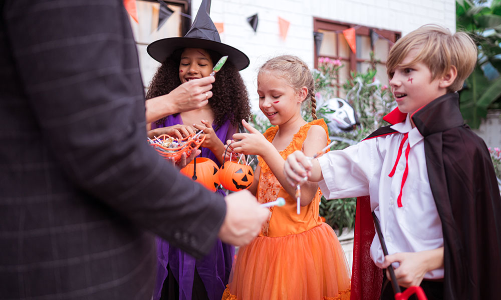 Parent checking individually wrapped Halloween treats with their child.